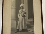 an old photo of a man in a white coat and hat holding a teddy bear