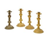 three gold candlesticks are sitting on a white surface