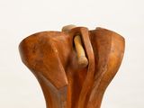 wooden sculpture of a hand holding a wooden object on a white pedestal