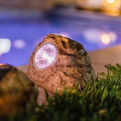 un rocher surmonté d'une lampe, près d'une piscine