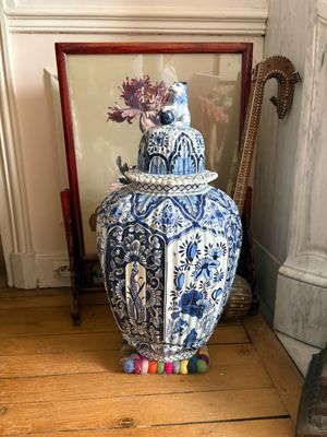 un vase bleu et blanc posé par terre à côté d'une photo encadrée