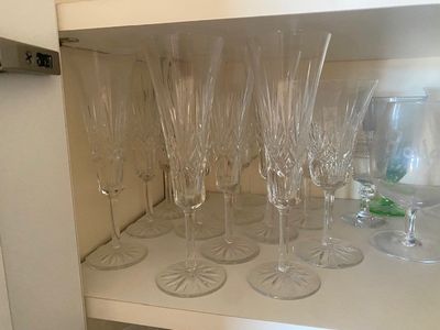 Des bouteilles et des verres sont alignés sur une étagère dans une cuisine.