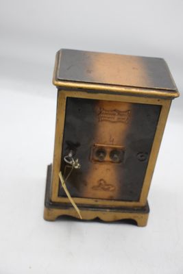 une petite horloge posée sur une surface blanche