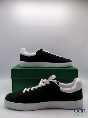 black and white sneakers with white laces on top of a green box