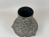 a black and white vase sitting on a white surface