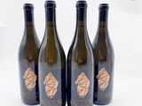 trois bouteilles de vin ornées de feuilles d'or, posées sur une surface blanche