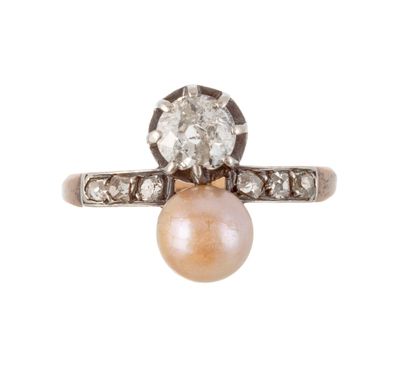un gros plan d'une bague sertie d'un diamant et d'une perle sur fond blanc