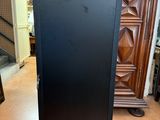 a black refrigerator sitting in a room next to a dresser