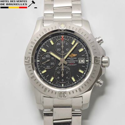 une montre en argent avec un cadran noir et des aiguilles jaunes