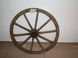 a wooden wagon wheel sitting on the floor next to a wall