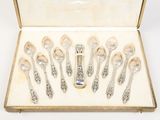 six silver spoons in a case with a spoon in the middle