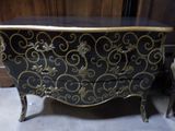 a black and gold chest of drawers next to a chair