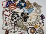 many different types of necklaces and bracelets laid out on a table
