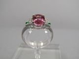un gros plan d'une bague rose et verte posée sur une surface transparente