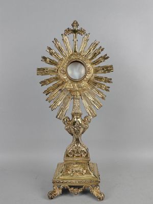 une statue en or représentant une personne tenant une croix, posée sur un socle