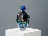 une bouteille en verre posée sur un socle blanc