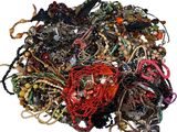 a pile of assorted bracelets and necklaces on a white surface