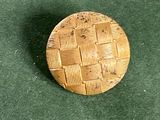 une image représentant un petit bouton en bois posé sur une surface verte