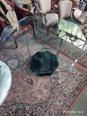 une table en verre avec un plateau en verre dans une pièce remplie de chaises