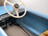 a steering wheel in the center of a small blue car