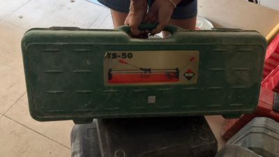 une femme tenant une mallette verte sur laquelle est posée une horloge