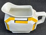 a white pitcher with a yellow and black stripe on it