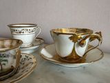 three cups and saucers on a table with a wall in the background