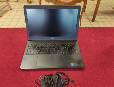 un ordinateur portable posé sur une table, avec un chargeur branché dessus