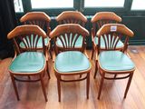 quatre chaises en bois aux assises vertes, placées devant une fenêtre
