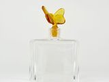 a glass bottle with a butterfly on top of it