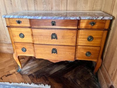 une commode en bois avec un plateau en marbre, placée dans un coin de la pièce