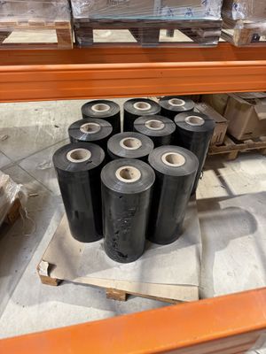 de nombreux rouleaux de plastique noir posés sur une étagère dans un entrepôt