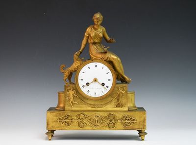 une horloge en or avec une femme assise dessus