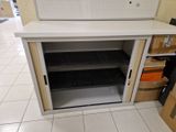 une petite armoire dont la porte est ouverte et dont le fond repose à même le sol