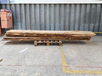 plusieurs pièces de bois sont empilées sur des palettes dans un entrepôt