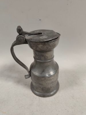 an old pewware pitcher with a handle on a white surface