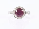 a close up of a ring with a ruby stone surrounded by diamonds