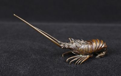 un gros plan d'un objet métallique représentant un homard posé sur une surface noire