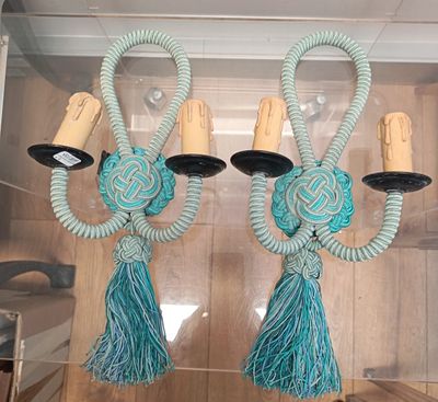two teal colored wall sconces with tassels hanging from them