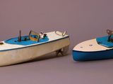 two toy boats sitting next to each other on a gray surface