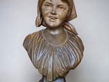 bronze bust of a young girl with a hat on her head