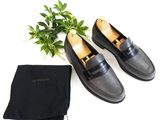 pair of black leather loafers with a black bag and a plant
