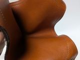 someone is holding a pair of brown leather shoes on a white surface