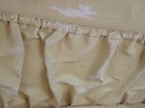a close up of a bed with a ruffled cover on it