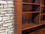 an image of a wooden bookcase against a stone wall