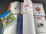 several children ' s books are open on a table with drawings on them