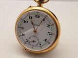 l'image d'une montre de poche en or posée sur une surface blanche