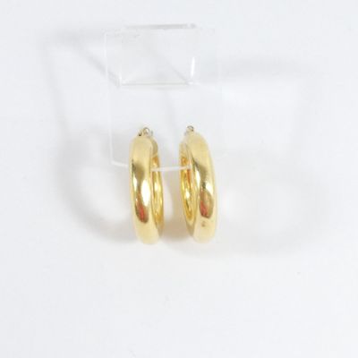 une paire de boucles d'oreilles créoles en or posée sur un présentoir transparent