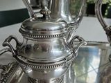 two silver teapots sitting on a tray on a table