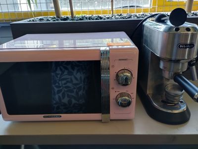 un micro-ondes rose posé sur un plan de travail, à côté d'une cafetière